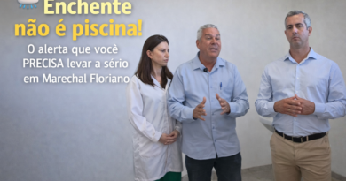 Prefeito de Marechal Floriano aparece ao lado de um secretário e uma médica dentro de uma unidade de saúde, alertando sobre os riscos do contato com água de enchente e a necessidade de procurar atendimento preventivo.