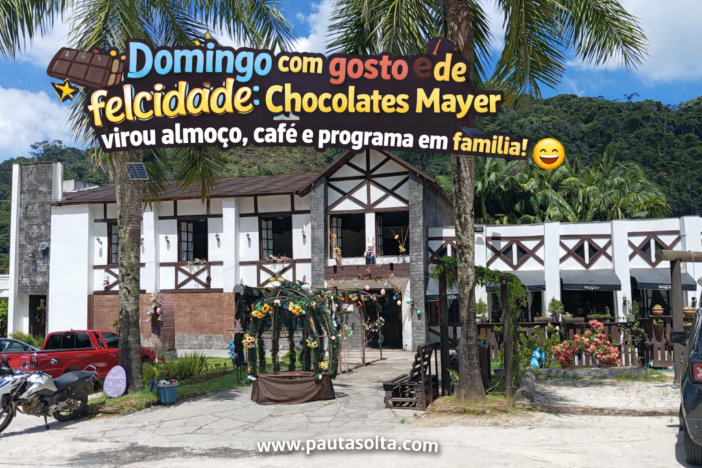 Fachada do Chocolates Mayer em Marechal Floriano, com arquitetura estilo europeu, cercada por palmeiras e montanhas ao fundo, em dia ensolarado, com título “Domingo com gosto de felicidade” e assinatura www.pautasolta.com
.
