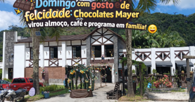 Fachada do Chocolates Mayer em Marechal Floriano, com arquitetura estilo europeu, cercada por palmeiras e montanhas ao fundo, em dia ensolarado, com título “Domingo com gosto de felicidade” e assinatura www.pautasolta.com .