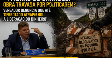 Vereador em sessão na câmara aponta durante fala, enquanto ao lado uma estrada de terra bloqueada com placa “recursos bloqueados por picuinha política” simboliza obra pública travada; manchete questiona atraso por politicagem.