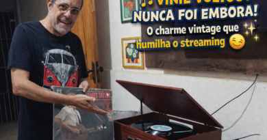 Homem sorrindo segura disco de vinil ao lado de toca-discos em funcionamento, destacando o retorno do vinil e a experiência musical analógica em contraste com o streaming digital.