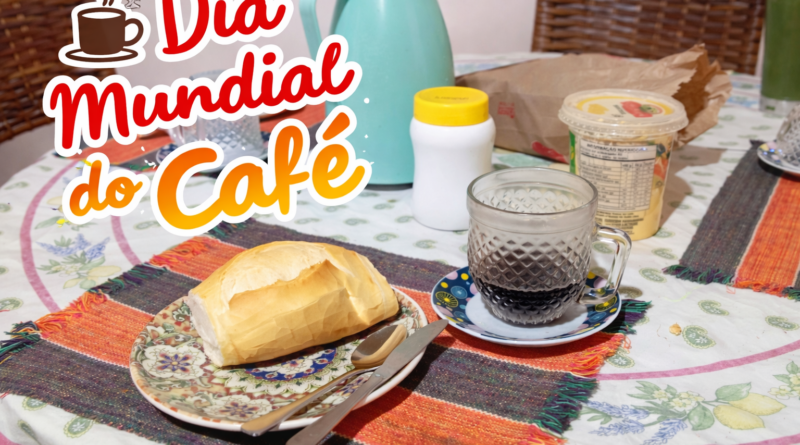 Café preto servido em xícara de vidro ao lado de pão francês em prato decorado sobre mesa posta, simbolizando o Dia Mundial do Café e o tradicional café da manhã brasileiro.