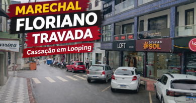 Rua central de Marechal Floriano com comércio local e carros estacionados, ilustrando o clima urbano em meio ao cenário de cassação do prefeito e instabilidade política na cidade.